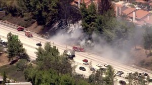 A vehicle fire spread to vegetation next to a condo complex and the 118 Freeway in Porter Ranch on Aug. 13, 2015. (Credit: KTLA)