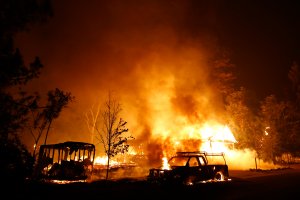 A car burns in front of a burning home during Valley Fire on Sept. 13, 2015, in Middletown, California. The fast-moving fire has consumed 40,000 acres and is currently zero percent contained. (Credit: Stephen Lam/ Getty Images)