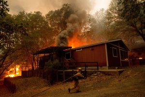 Firefighters attempt to save a burning house during the Valley Fire in Seigler Springs, California, on Sept. 13, 2015. Gov. Jerry Brown declared a state of emergency that day as raging wildfires spread in the northern part of the drought-ridden state, forcing thousands to flee the flames. (Credit: Josh Edelson/AFP/Getty Images)