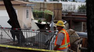 A worker inspects the scene near a red-tagged home after a torrent of water surged through the Rubio Wash and destroyed the back of the home during Tuesday's rainstorm. (Credit: Rick Loomis / Los Angeles Times)