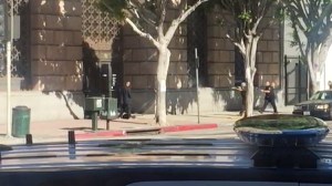 A man is seen outside a Chase bank in downtown Los Angeles as police responding to a bomb threat arrive with guns drawn. (Credit: Paul Bortoli)