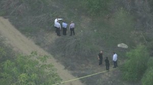 Detectives investigate in Debs Park, where two female bodies were discovered Oct. 28, 2015. One of the bodies has been blurred in this image. (Credit: KTLA)