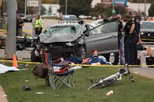 Emergency officials stand over the car that was involved after a suspected drunk driver crashed into a crowd of spectators during the Oklahoma State University homecoming parade near the Boone Pickens Stadium on October 24, 2015 in Stillwater, Oklahoma. The car slammed into a crowd, killing three and injuring at least 22 before the Kansas Oklahoma State football game. (Credit: J. Pat Carter/Getty Images)