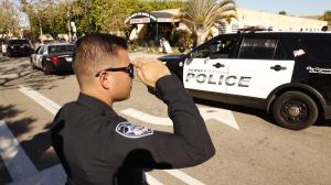 Bell Gardens police Officer Steven Perez salutes as the coroner's van departs from the scene where Downey police Officer Ricardo Galvez was found shot to death in the driver's seat of his vehicle in a Downey parking lot on Nov. 19, 2015. (Credit: Al Seib / Los Angeles Times)