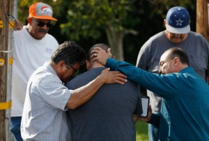 A group of men embrace in prayer on on Dec. 3, 2015, outside the crime scene where the suspects in the shooting at the Inland Resource Center were killed in San Bernardino. (Credit: Sean M. Haffey/Getty Images)