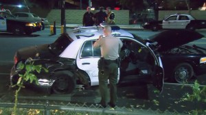 A sheriff's deputy takes photos of a damaged patrol car after a crash in West Hills on Dec. 11, 2015. (Credit: KTLA)