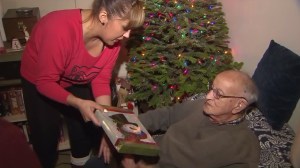 Herman Perry, a Venice resident and World War II veteran, opens presents on Dec. 21, 2015, that were donated by LAPD officers. (Credit: KTLA) 