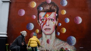 Floral tributes are left beneath a mural of British singer David Bowie, painted by Australian street artist James Cochran, aka Jimmy C, following the announcement of Bowie's death, in Brixton, south London, on Jan. 11, 2016. British music icon David Bowie died of cancer at the age of 69, drawing an outpouring of tributes for the innovative star famed for groundbreaking hits like 'Ziggy Stardust' and his theatrical shape-shifting style. (Credit: CHRIS RATCLIFFE/AFP/Getty Images)