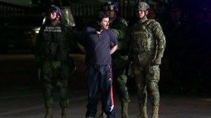 Mexican forces escorted Joaquin "El Chapo" Guzman out of an armored vehicle and into a helicopter late Friday night following his arrest after months on the run. (Credit: CEPROPIE via CNN)