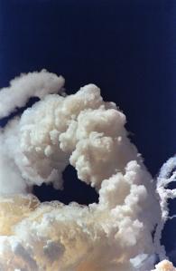 A solid fuel rocket booster disappears behind the contrail of the explosion of the space shuttle Challenger 28 January 1986 over Kennedy Space Center as debris from the orbiter begins to fall to earth. (Photo credit should read BOB PEARSON/AFP/Getty Images)