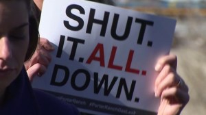 An activist holds a sign at a news conference related to the Porter Ranch-area gas leak on Jan. 11, 2016. (Credit: KTLA)