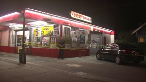 A police officer stands outside the Bossy Dairy in San Bernardino, where the owner was fatally shot during an armed robbery on Jan. 29, 2016. (Credit: KTLA)