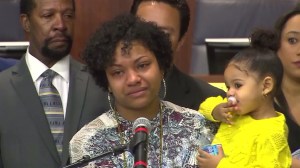 Dramika Pegus, center, talks about her husband, Jordan Love, who was fatally shot in Carson on Feb. 27, 2016. Love's 2-year-old daughter is pictured to the right, and his father, Jose Love, is left. (Credit: KTLA)