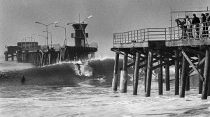 In a Feb. 11, 1983, Times file photo, a surfer rides a wave through a missing section of the Seal Beach Pier that was washed out by a Jan. 27 storm. (Credit: Cliff Otto/Los Angeles Times)