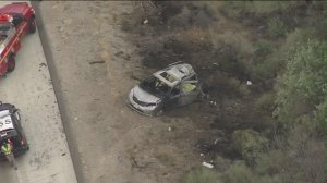 A burned-out minivan is seen near the southbound side of the 5 Freeway in Gorman on June 28, 2016. (Credit: KTLA)