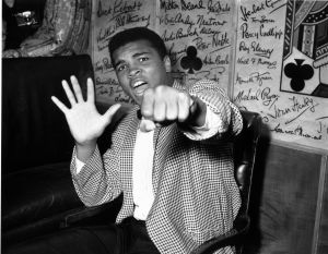 Supremely confident American boxer Cassius Clay holds up five fingers in a prediction of how many rounds it will take him to knock out British boxer Henry Cooper. (Photo by Kent Gavin/Keystone/Getty Images)