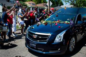 The hearse carrying boxing legend Muhammad Ali drives past his childhood home where mourners throw flowers as they pay their respects on June 10, 2016, in Louisville, Kentucky. (Credit: JIM WATSON/AFP/Getty Images)