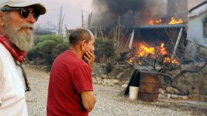 Residents Sal Blanco, left, and Nelson Hernandez watch a neighbor's house burn along Kelso Valley Road east of Lake Isabella during the Esrkine fire Friday. (Credit: Wally Skalij / Los Angeles Times)