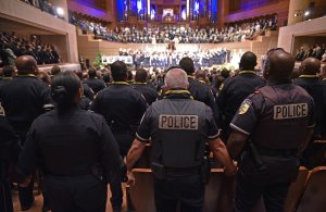 Police join hands during the singing of "The Battle Hymn of the Republic" during an interfaith memorial service for the victims of the Dallas police shooting at the Morton H. Meyerson Symphony Center on July 12, 2016 in Dallas, Texas. (Credit: MANDEL NGAN/AFP/Getty Images)