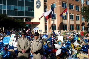 Police officers stand next to a growing memorial of flowers and balloons in front of the Dallas Police Department headquarters on July 13, 2016 in Dallas, Texas. (Credit: Justin Sullivan/Getty Images)