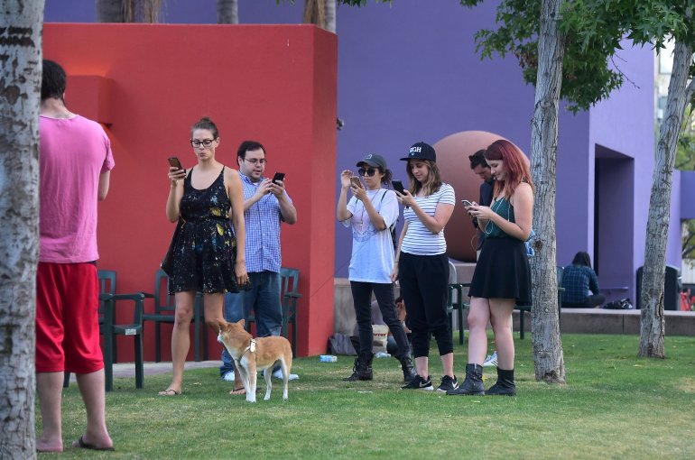 People look at their phones while playing "Pokemon Go" on July 13, 2016, at Pershing Square in downtown Los Angeles. (Credit: FREDERIC J. BROWN/AFP/Getty Images)