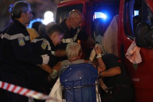 Rescue workers help an injured woman to get in a ambulance on July 15, 2016, after a truck drove into a crowd watching a fireworks display in the French Riviera town of Nice. (Credit: VALERY HACHE/AFP/Getty Images)