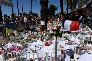 People gather around the makeshift memorial where flowers, candles and messages were laid in Nice on July 16, 2016, in tribute to the victims of the deadly attack on the Promenade des Anglais seafront which killed 84 people. (Credit: BORIS HORVAT/AFP/Getty Images)