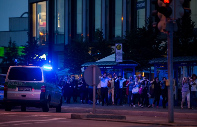 Police officers escort people with their hands raised from inside the shopping center as they respond to a shooting at the Olympia Einkaufzentrum (OEZ) at July 22, 2016, in Munich, Germany. (Credit: Joerg Koch/Getty Images)