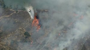 A helicopter makes a water drop on a brush fire burning in the Hollywood Hills on July 19, 2016. (Credit: KTLA)
