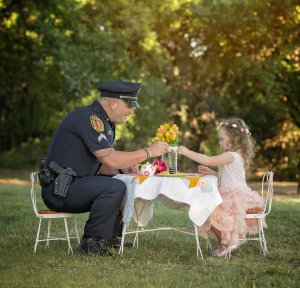 Corporal Patrick Ray sits down at a tea party with 2-year-old Bexley one year after saving her life. (Credit: Chelle Cates Photography)