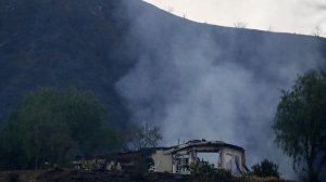 A smoldering home off the 26700 block of Iron Canyon Road on Sunday morning. (Credit: Francine Orr / Los Angeles Times)