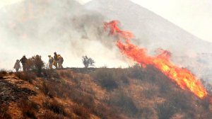 Heat from flames push firefighters back as they monitor a flare up in brush along Soledad Canyon Road near Acton on Monday. (Credit: Al Seib/Los Angeles Times)