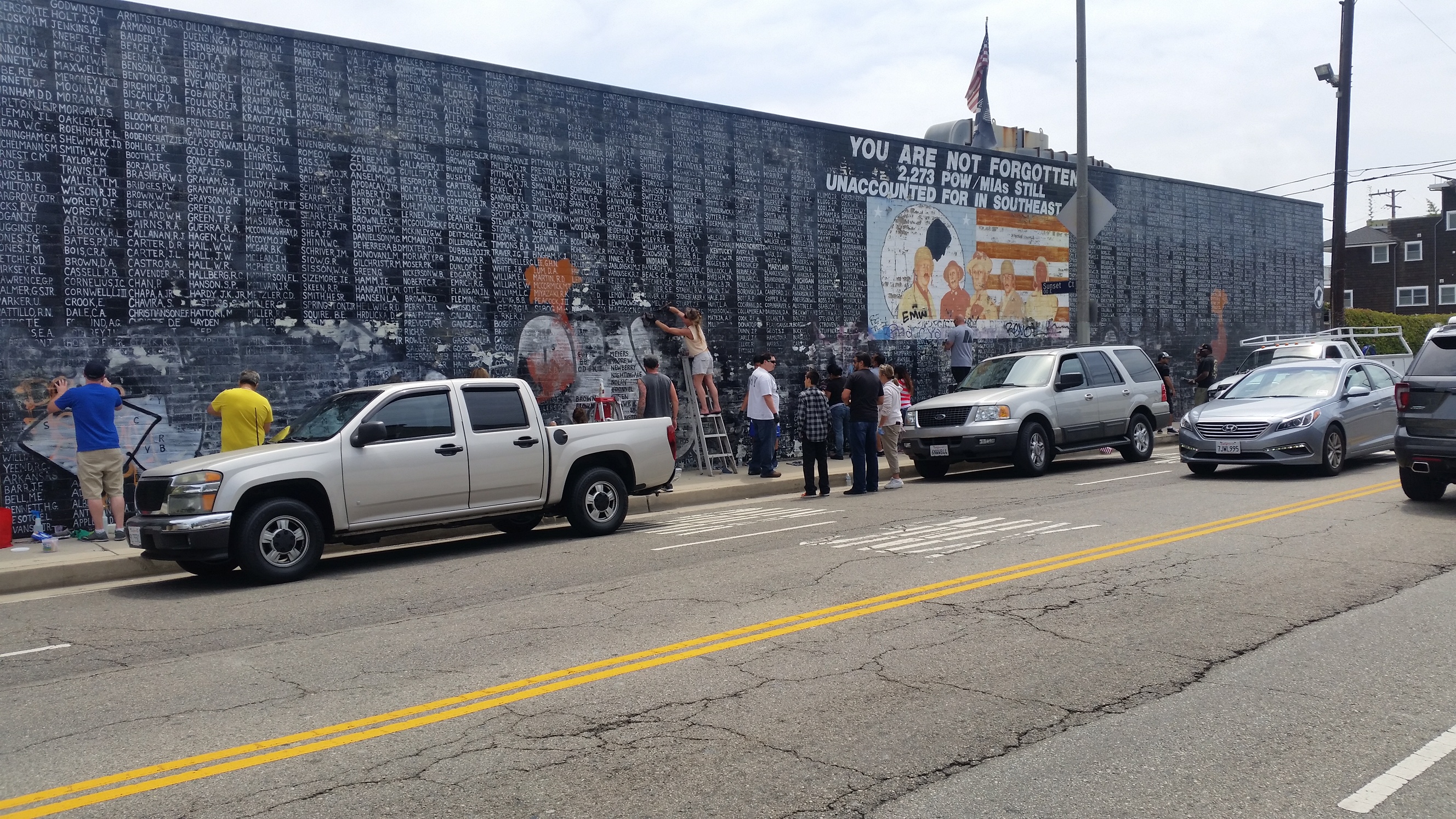 In an undated photo, volunteers help clean a Vietnam War veterans memorial wall that was vandalized by taggers in May. (Credit: Los Angeles County Sheriff's Department)