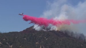 A plane drops fire retardant on the Pilot Fire on Aug. 9, 2016. (Credit: KTLA)