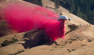 A plane drops fire retardant while battling the Soberanes Fire in Carmel Highlands on July 23, 2016. (Credit: NOAH BERGER/AFP/Getty Images)