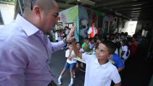 Juan Carlos Rodriguez, left, Title I coordinator, gives a high-five to second-grader Armando Rodriguez, 7, during lunch on the first day of school at Hadden Elementary School in Pacoima in August 2013. (Credit: Francine Orr / Los Angeles Times)