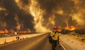 A firefighter uses his radio to alert that the Blue Cut fire is burning on both sides of Highway 138 in Phelan. (Credit: Gina Ferazzi / Los Angeles Times)