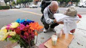 Neighborhood resident Fred Purdue adds a baseball cap, baby blanket and votive candles to a makeshift memorial at the intersection of 9th Street and Locust Avenue in Long Beach, where a a mother and her daughter were shot and killed on Saturday night. (Credit: Luis Sinco / Los Angeles Times)