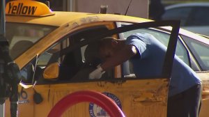 An investigator takes evidence from the taxi that was driven by a man who was killed in Hollywood Hills on Aug. 14, 2016. (Credit: KTLA)