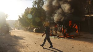 A Syrian man walks past a bus set ablaze following a reported air strike in Aleppo on Sept. 25, 2016.(Credit: Ameer Alhalbi/AFP/Getty Images)
