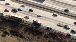 A school bus that caught fire is at left, and students that were moved of the bus are at right along the 210 Freeway in Lake View Terrace on Sept. 29, 2016. (Credit: KTLA)