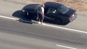 A pursuit driver stopped on the 215 Freeway in San Bernardino and got out of his vehicle with a long object in his hand on Sept. 26, 2016. (Credit: KTLA)