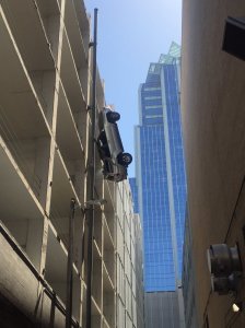 A Texas man drove his car off the top of a parking garage in downtown Austin Friday, leaving it dangling several stories above an alley. (Credit: Austin Fire Department)