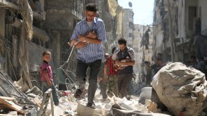 Syrian men carrying babies make their way through the rubble of destroyed buildings following a reported air strike on the rebel-held Salihin neighbourhood of the northern city of Aleppo, on Sept. 11, 2016. (Credit: Ameer Alhalbi/AFP/Getty Images)