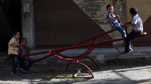 Syrian boys play on a see-saw in the rebel-held town of Arbin as they celebrate the Muslim Eid al-Adha holiday on Sept. 13, 2016. (Credit Amer Almohibany/AFP/Getty Images)