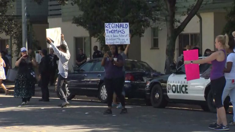 Protesters hold signs less than 12 hours after Reginald Thomas was killed in an altercation with police in Pasadena on Sept. 30, 2016. (Credit: KTLA)
