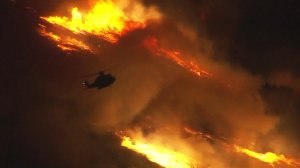 A helicopter is seen battling a brush fire at the Aliso Canyon gas facility near Porter Ranch on Oct. 18, 2016. (Credit: KTLA)