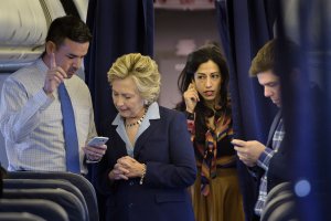 Democratic presidential nominee Hillary Clinton looks at national press secretary Brian Fallon's smart phone while on her plane with aide Huma Abedin and traveling press secretary Nick Merrill at Westchester County Airport Oct. 3, 2016, in White Plains, New York. (Credit: BRENDAN SMIALOWSKI/AFP/Getty Images)