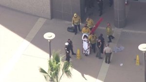 Firefighters take a woman to a waiting ambulance outside the courthouse in Chatsworth on Oct. 31, 2016. (Credit: KTLA)