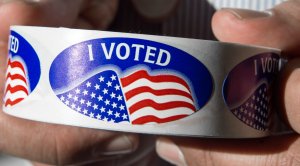 An election official holds a roll of the 'I voted' stickers at Centreville High School in Centreville, Virginia March 1, 2016, during the Super Tuesday primary voting. (Credit: PAUL J. RICHARDS/AFP/Getty Images)